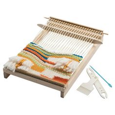 a weaving machine with scissors and yarn on the table next to it is an object that looks like a bed