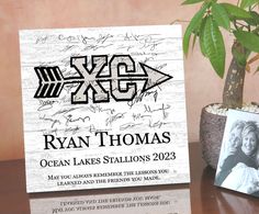 a wooden plaque with an image of ryan thomas on it next to a potted plant