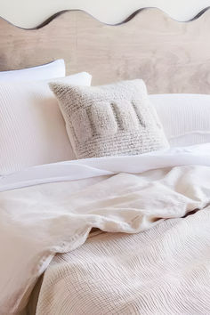 a bed with white sheets and pillows on it