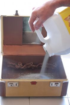 a person is pouring water into a suitcase