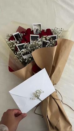 someone is holding a bouquet of flowers and an envelope with some photos on the front