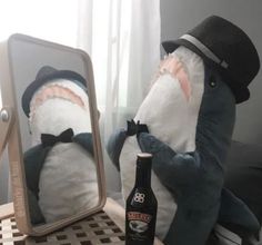 there is a stuffed shark with a bottle in front of it and a mirror behind it