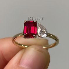 a person holding a red and white ring with two pear shaped diamonds on it's side