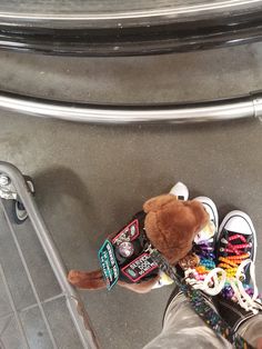 a teddy bear sitting on top of a pile of shoes next to a person's leg