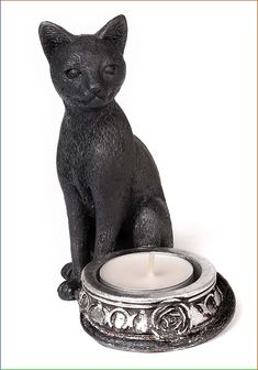 a black cat sitting on top of a candle holder