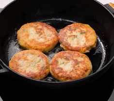 four fried food items cooking in a black skillet on the stove top next to some bread