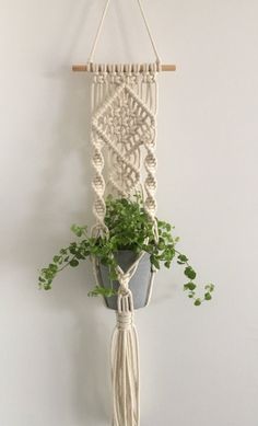 a macrame plant hanger with a potted plant in it on a white wall