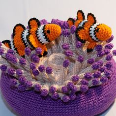 two clown fish sitting on top of a purple crocheted hat