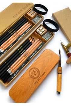 an assortment of pencils and pens in a wooden case next to a pair of scissors