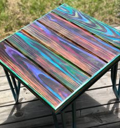 a multicolored wooden table sitting on top of a wooden deck next to grass