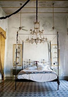 a bedroom with a bed, chandelier and pictures on the wall above it