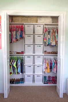 an organized closet with baskets and clothes hanging on the wall next to shelves filled with children's clothing