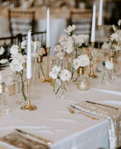 the table is set with white flowers and candles