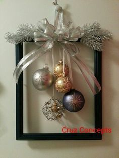 christmas ornaments are hanging on the wall in a frame with ribbon and bow around them