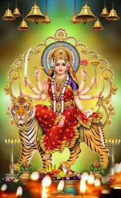 the hindu goddess sitting on top of a tiger in front of some candles and lights