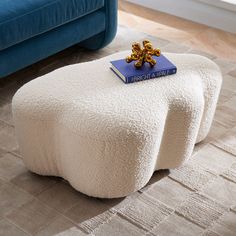 a white ottoman sitting on top of a rug next to a blue couch