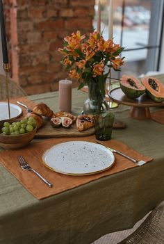 the table is set with plates and bowls of food on it, including watermelon