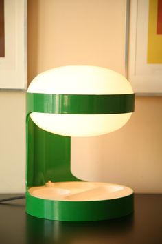 a green table lamp sitting on top of a wooden table next to a framed picture