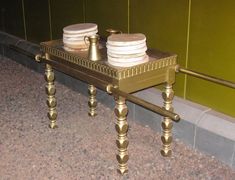 two stacks of plates sitting on top of a metal table in front of a green wall