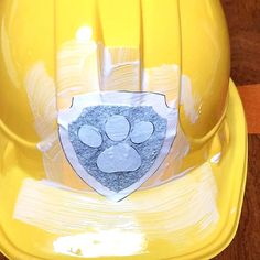 a yellow hard hat with a paw print on it