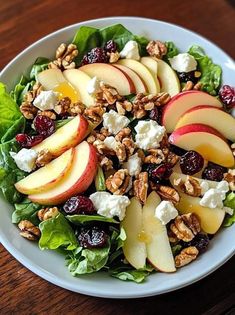 a salad with apples, cranberries, walnuts and feta cheese on it