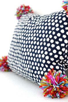 a black and white pillow with colorful pom poms