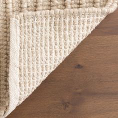 a close up view of a rug on the floor with wood floors and white carpet