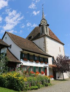 a white building with green shutters and a clock tower