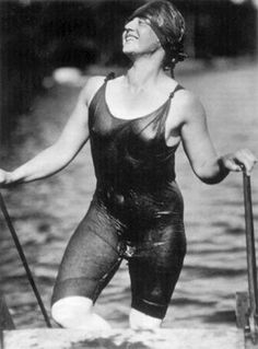 an old photo of a woman in wetsuit standing on a paddle board and holding two oars