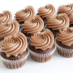 several chocolate cupcakes with frosting on them are arranged in a row and stacked