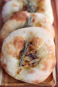 three flat breads with herbs on them sitting on a cutting board next to each other