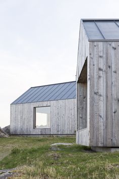 two wooden buildings sitting on top of a grass covered field