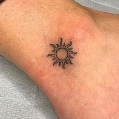 a small sun tattoo on the foot of a person's left arm and wrist