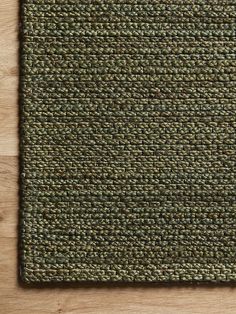 an area rug on top of a wooden floor with a brown and green color scheme