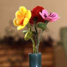 three felt flowers in a blue vase on a table