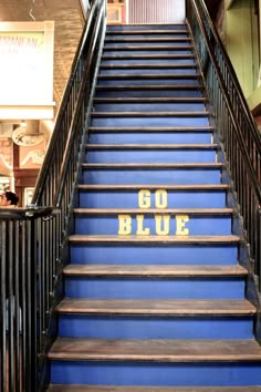 blue stairs with the words go blue painted on them in gold letters and black railings