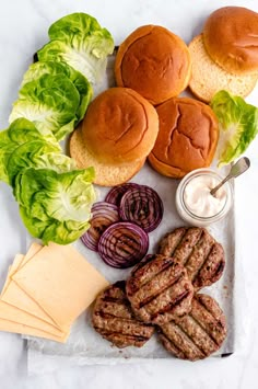 hamburgers, lettuce and cheese are on a plate with other food items