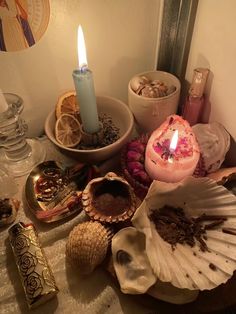 an assortment of seashells, candles and other items are on the table next to each other