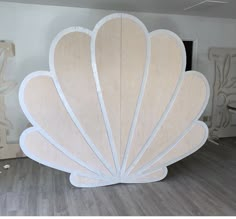 a large shell shaped sculpture sitting on top of a hard wood floor next to a white wall