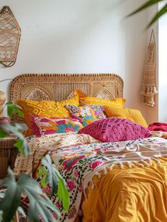 a bed with colorful blankets and pillows next to a potted plant in a room