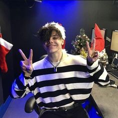 a man in a black and white striped shirt making the peace sign