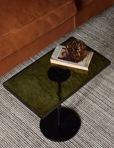 a coffee table with a book on it in the middle of a room next to a couch