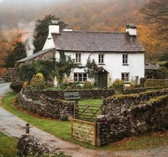 a white house sitting on the side of a lush green hillside next to a road