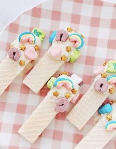 four ice cream cones decorated with unicorns and stars on a pink checkered plate