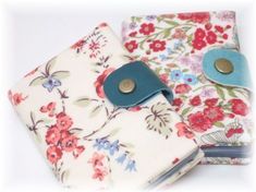 two small wallets with flowers on them, one is blue and the other has red