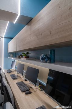 a long table with several computers on it in an office space that has blue and white walls