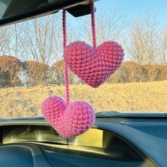 two pink crocheted hearts hanging from a car windshield