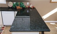 a kitchen with black granite counter tops and white cabinets in the corner, along with an island