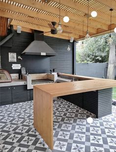 an outdoor kitchen with black and white checkered flooring on the outside, and wood pergolated roof