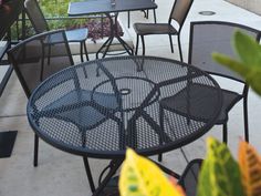 an outdoor table and chairs on a patio with plants in the backgrounge